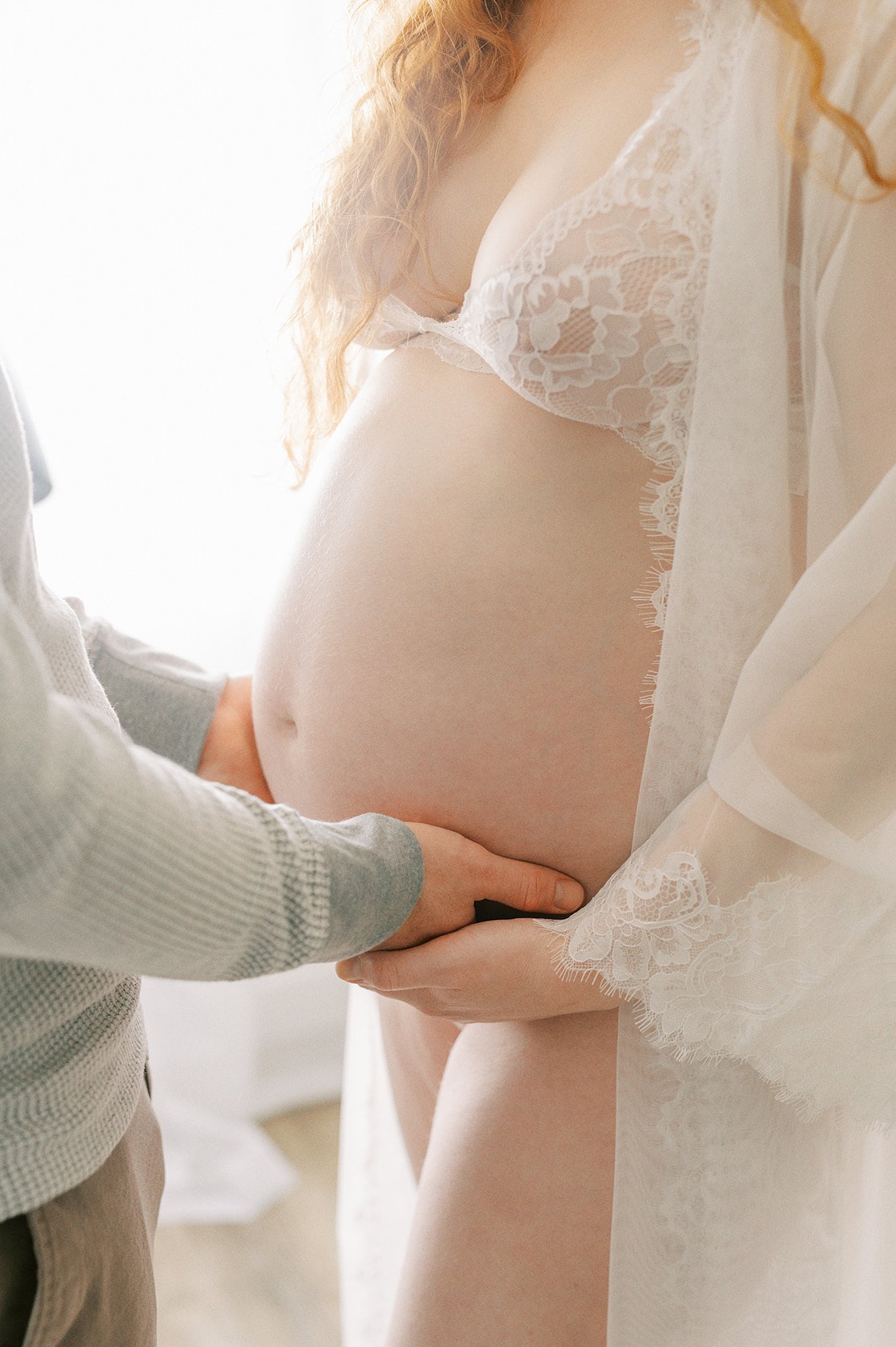 Details of a father to be placing his hands under mother's bump New Day Midwifery