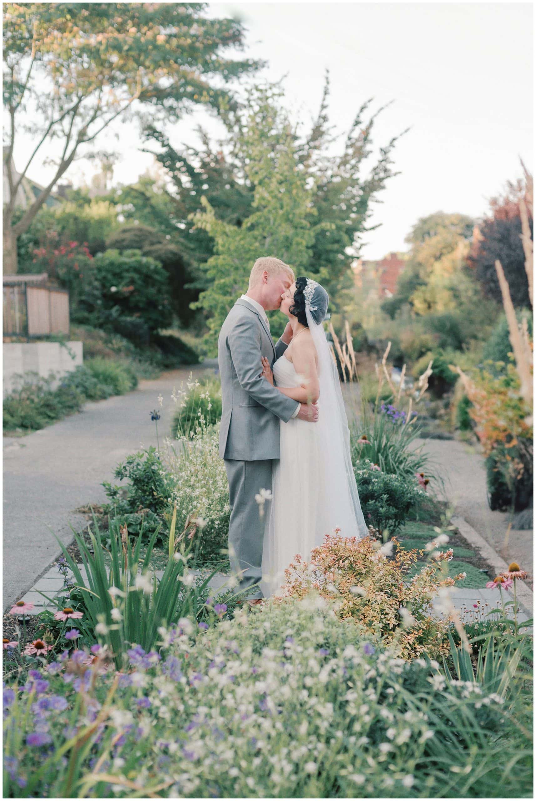 Newlyweds kiss while standing in a flower garden Seattle Small Wedding Venues